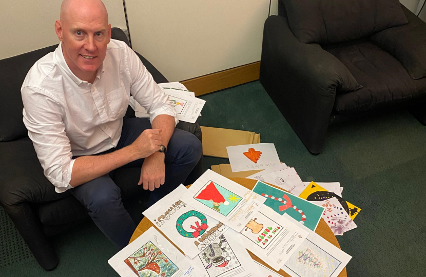 Kieran sitting in front of Christmas card competiton entries