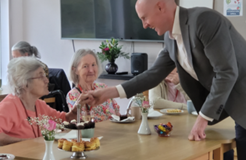 Kieran shaking hands and smiling with female resident of Saxonwood