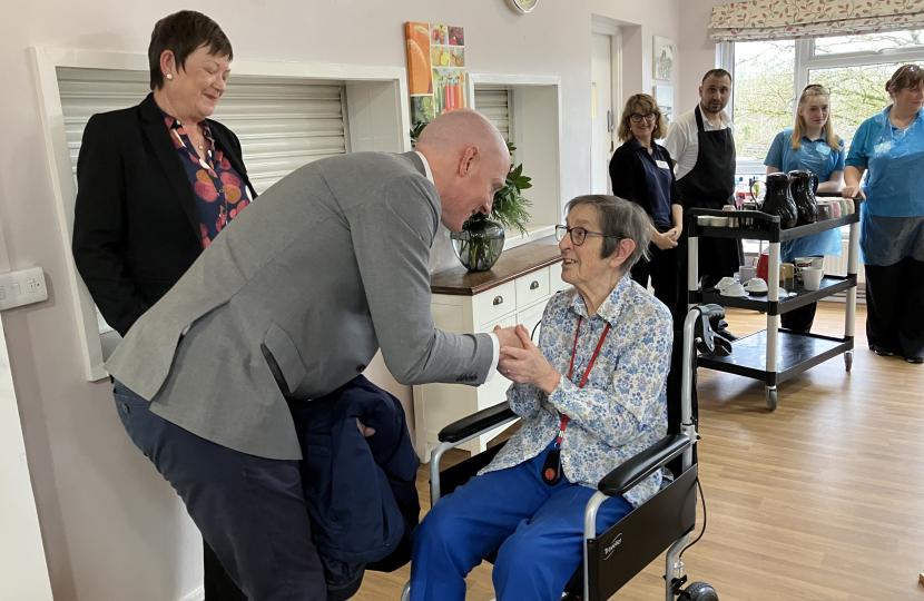 Kieran bending over to talk to female Saxonwood resident who is seated in a wheelchair