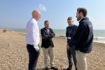 Kieran standing on beach with officials from Environment Agency in discussion about water pollution