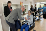 Kieran bending over to talk to female Saxonwood resident who is seated in a wheelchair