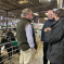 Kieran Mullan talking to local farmers Matt Ford and John Marland in barn with calves behind 