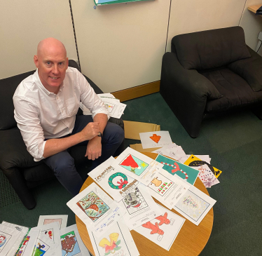 Kieran sitting in front of Christmas card competiton entries