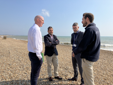 Kieran standing on beach with officials from Environment Agency in discussion about water pollution