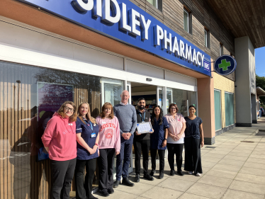 Kieran with Sukhy Uppal and the Sidley pharmacy teamm standing outside Sidley pharmacy