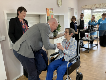 Kieran bending over to talk to female Saxonwood resident who is seated in a wheelchair